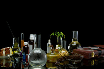 Medical jars with reagents and a plant with a leather suitcase on a black background