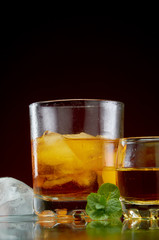 Strong alcohol in a transparent glass with ice on a red background