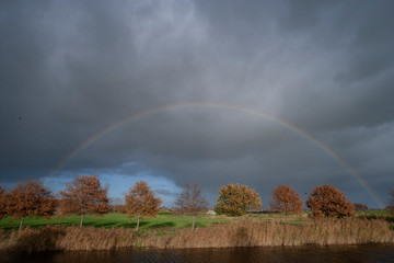 Autumn colors. Fall. Netherlands. Rainbow and rain-clouds