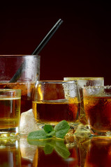 Glasses with strong alcoholic drinks with ice and mint on a red background