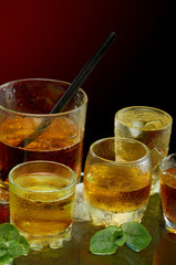 Set of different alcoholic cocktails with ice and mint on red background