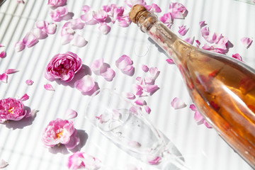 bottle of pink sparkling wine and glass on a white background with pink roses