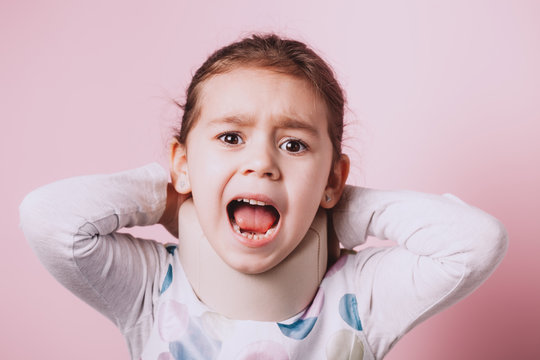 Portrait Of Little Girl Wearing Neck Brace On Pink Background.