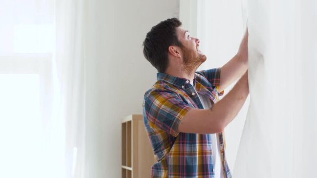 people concept - young man opening window curtain at home