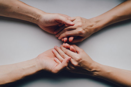 Closeup on two young lovers holding hands at a table. Hands holding hands. Hdns together.
