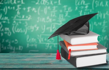 Graduation hat on stack books on wooden table at the classroom