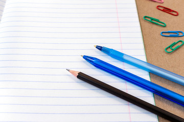 composition with notebook blank page colorful pencil, pen mock-up Back to school concept with stationery office supplies on a brown craft paper background with copy space top view