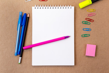 composition with notebook blank page colorful pencil, pen mock-up Back to school concept with stationery office supplies on a brown craft paper background with copy space top view