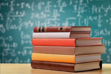 Stack colorful books on a school blackboard background