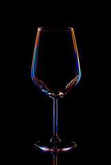 Glass for wine on a black background, multi-colored contours.