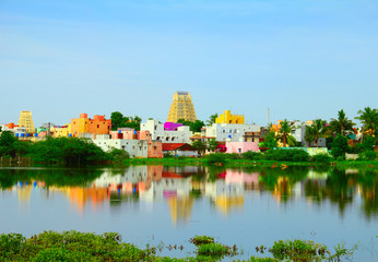 Beautiful scenic view of sacred city Kanchipuram (Kanchi) with colorful traditional houses, gopura of Hindu Temple bright foliage reflekted at calm lake waters, Tamil Nadu, South India - obrazy, fototapety, plakaty