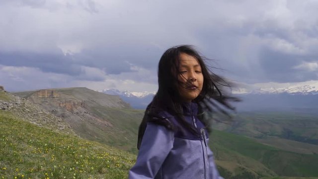 little asian girl spinning in the wind on a background of mountains