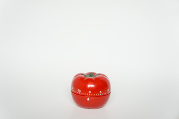 Close up view of mechanical tomato shaped kitchen clock timer for cooking & studying. Used for pomodoro technique for time and productivity management. Isolated on white background, set at 0 minutes.