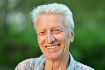 Smiling senior man posing in summer park