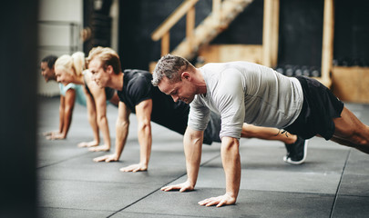 Fit people doing pushups together during a gym exercise class