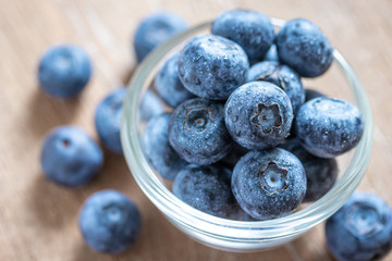 Blueberries in a glass bowl on wooden table and texture, fresh fruit with water droplet