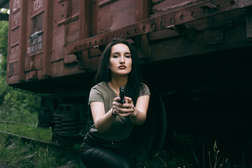 Obraz na płótnie Canvas Powerful Woman Holding Gun Action Movie Style. Train adventure. Military girl with .
