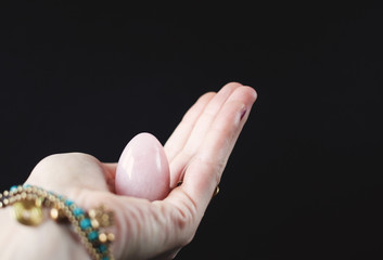 woman holding in hand a vaginal (yoni) egg. Rose quartz crystal jade egg. Copy space