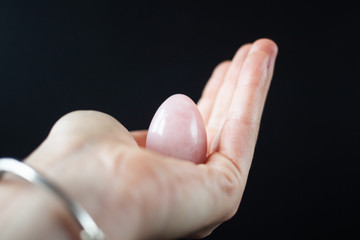 woman holding in hand a vaginal (yoni) egg. Rose quartz crystal jade egg. Copy space