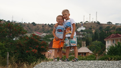 Two small kids playing together outdoors standing on the pile of the gravel