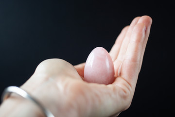 woman holding in hand a vaginal (yoni) egg. Rose quartz crystal jade egg. Copy space