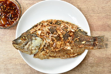 batter fried mango fish topping chop garlic on plate dipping sweet tamarind sauce