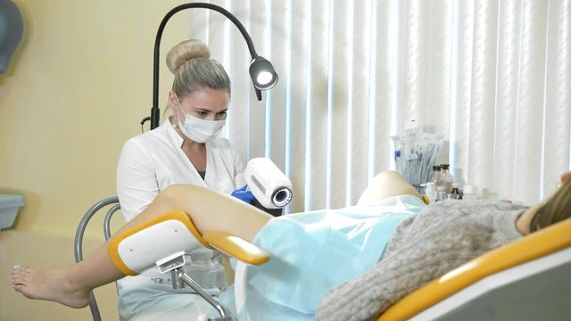 Patient and doctor in the gynecologists office. Doctor gynecologist looking into digital colposcopy microscope examining female illness