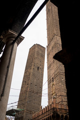 view of garisenda and asinelli medieval leaning towers in Bologna city center framed and seen from characteristic colonnade on a cloudy day