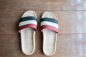 Slipper weave by handmade on wooden floor surface background. Pair of shoe on red and blue colour ready to ware at home. Concept of comfort home relax and holiday free time.