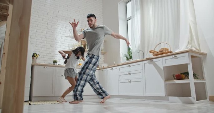 Pretty interracial couple wearing pyjamas funnily dancing and singing early in morning, preparing for new day, spending time together, having fun 4k