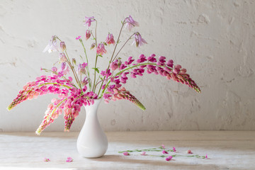 pink summer flowers in white vase on white old background