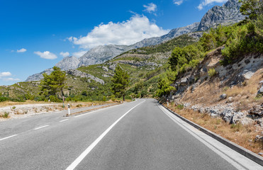 Mountain highway with blue sky and rocky mountains on a background
