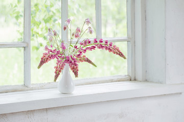 pink summer flowers in vase  on white old windowsill