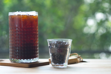 Cold brewed iced coffee in tall glass with coffee beans