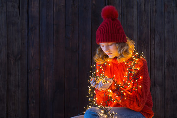 girl in red hat with christmas light on wooden background