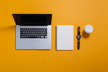 flat lay of laptop, notebook and coffee on yellow background