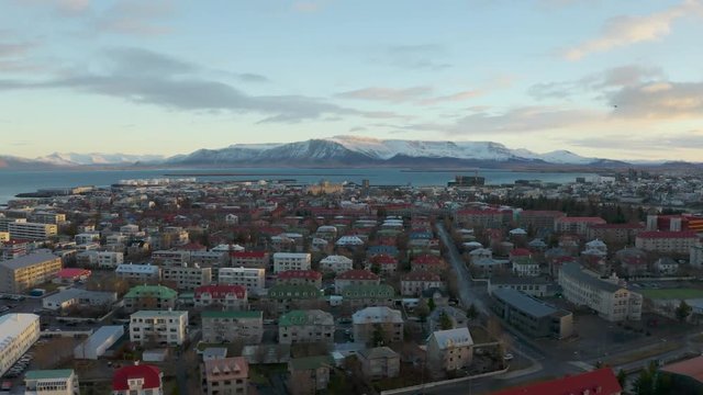 Aerial drone shot  dolly over Reykjavik with the iconic mountain ranges on the horizon. on a clear winter day in Iceland, Europe. With dramatic clouds at sunset.