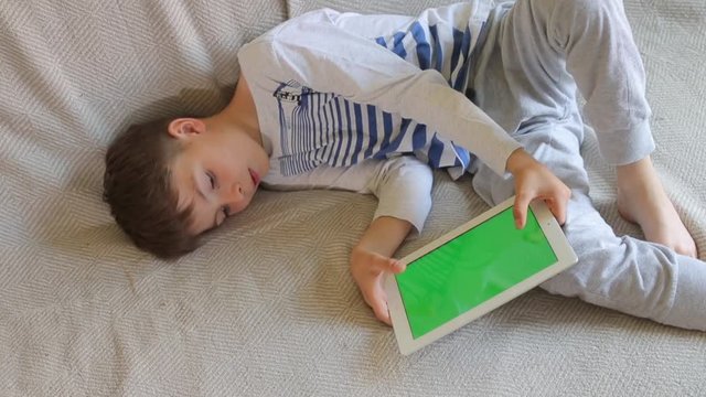 teenager lies and plays on the tablet