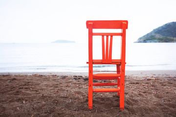 Empty retro orange wooden chair on the beach with copy space