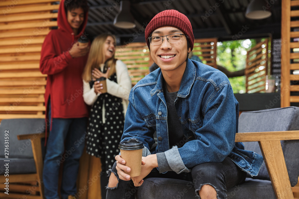 Wall mural Smiling asian teenager sitting outdoors