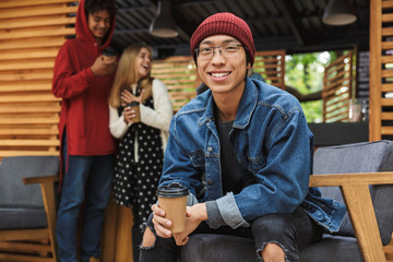 Smiling asian teenager sitting outdoors