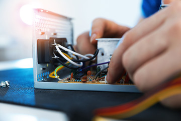 Male technician repairing power supply unit at table, closeup