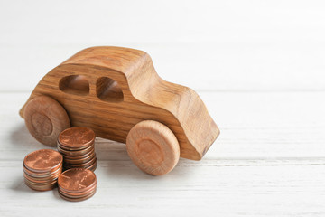 Car model and coins on white wooden background. Space for text