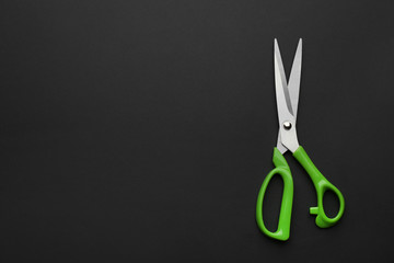 Pair of sharp scissors on dark background, top view. Space for text