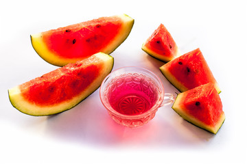 Detoxifying Watermelon seed's tea in a transparent glass cup along with watermelon pieces in triangle shape isolated on white.