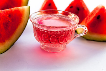 Detoxifying Watermelon seed's tea in a transparent glass cup along with watermelon pieces in triangle shape isolated on white.