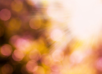 Obraz premium Summer abstract bokeh background in soft warm pastel orange and pink tones with sun rays. Beautiful bokeh summer sunlight background.