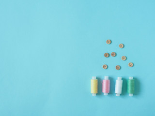 Spools of thread, buttons. Accessories for sewing on a blue background. Set for needlework in the top view.