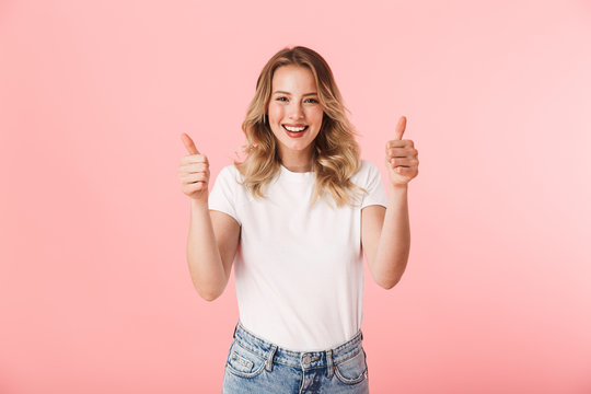 Happy young blonde woman posing isolated over pink wall background showing thumbs up gesture.