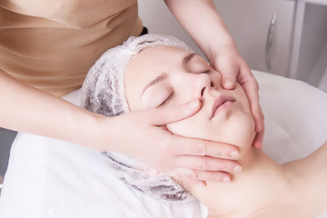 Fototapeta na wymiar Closeup of young woman receiving face massage from massage therapist.